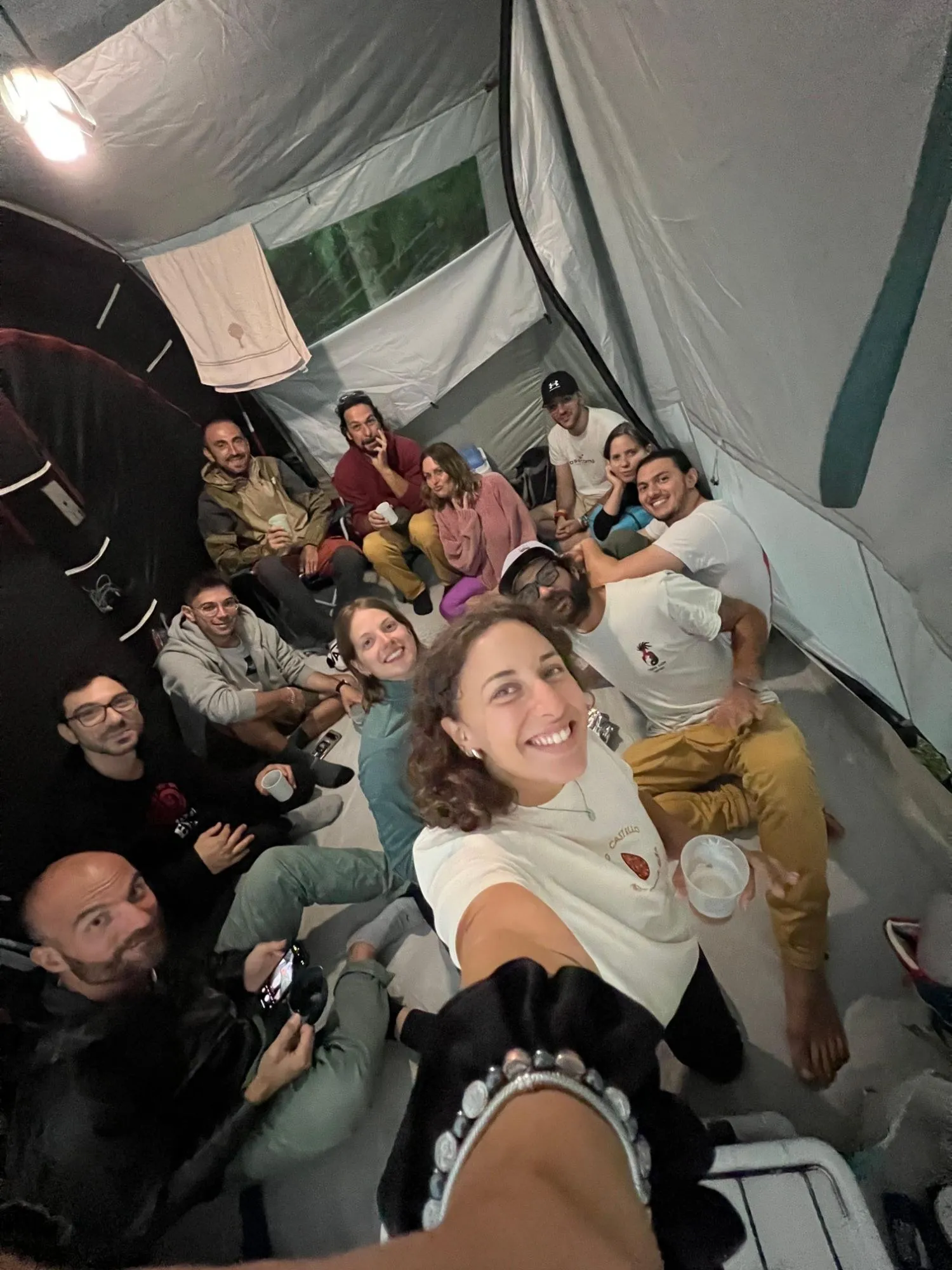 Selfie di gruppo dentro una grande tenda durante un campeggio, tutti sorridenti